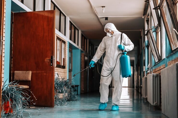full-length-worker-sterile-uniform-with-face-mask-holding-sprayer-with-disinfectant-spraying-school-hallway_232070-9971